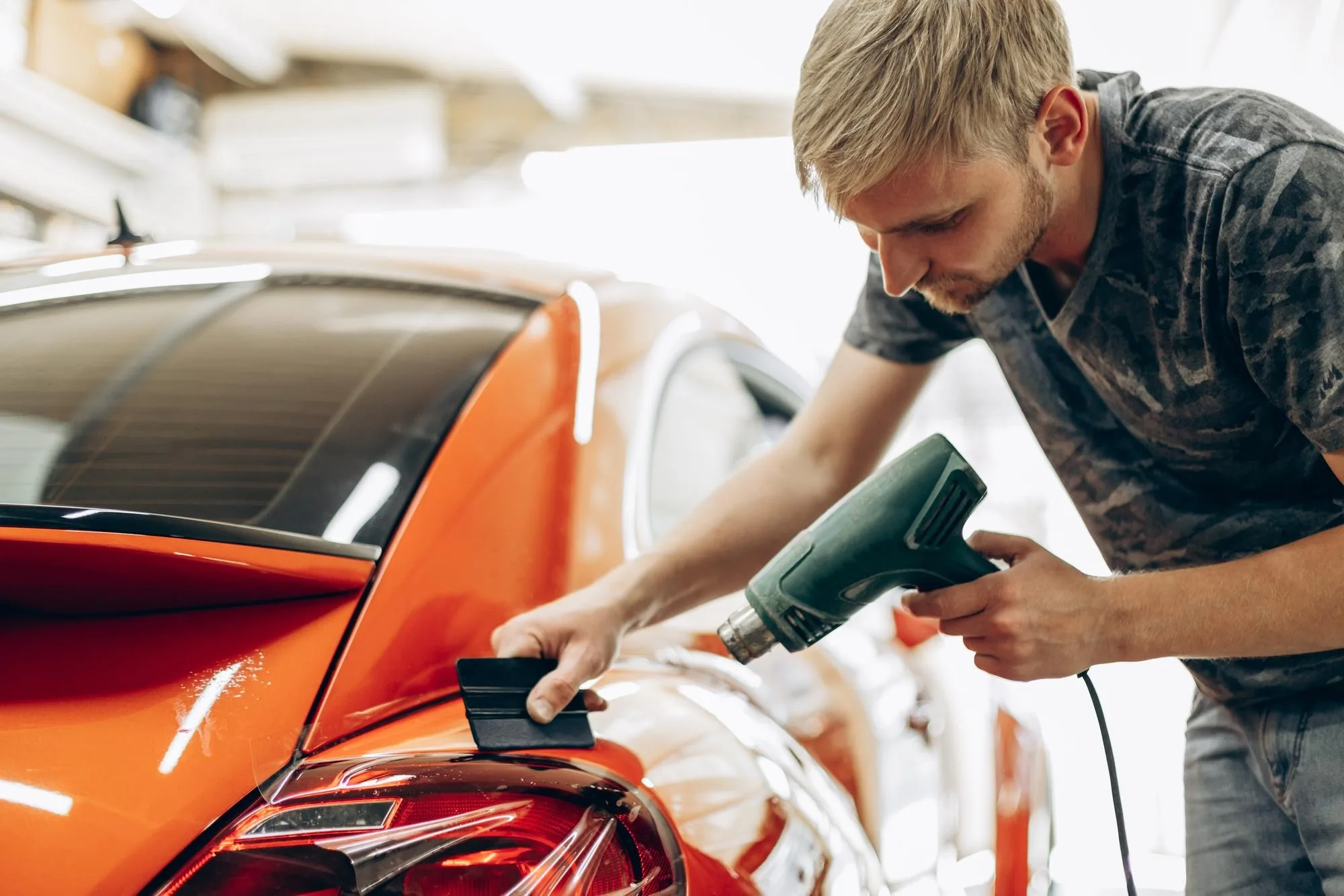 Paint protection film being applied to a car bonnet in a workshop
